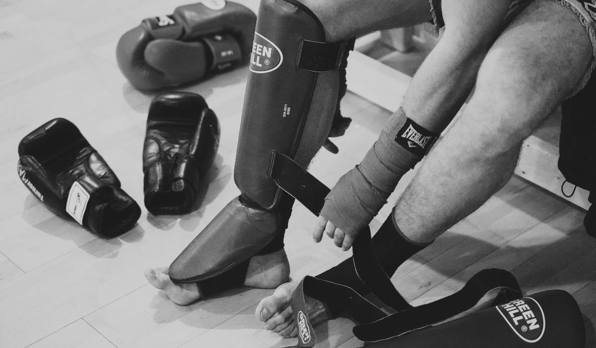 A muay thai student is sitting on a chair to put knee pads.