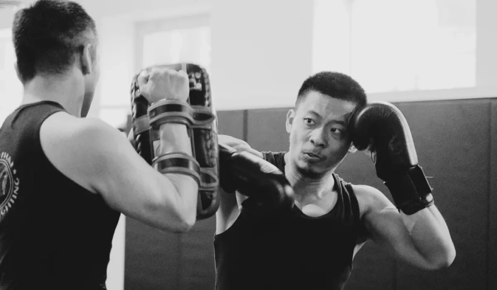 Muay thai instructor and a student training in a gym.